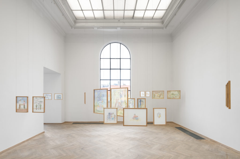 Et lyst udstillingsrum med mange trærammer hængende frit fra loftet. Hver ramme indeholder akvarelmotiver malet på opspændt silke.