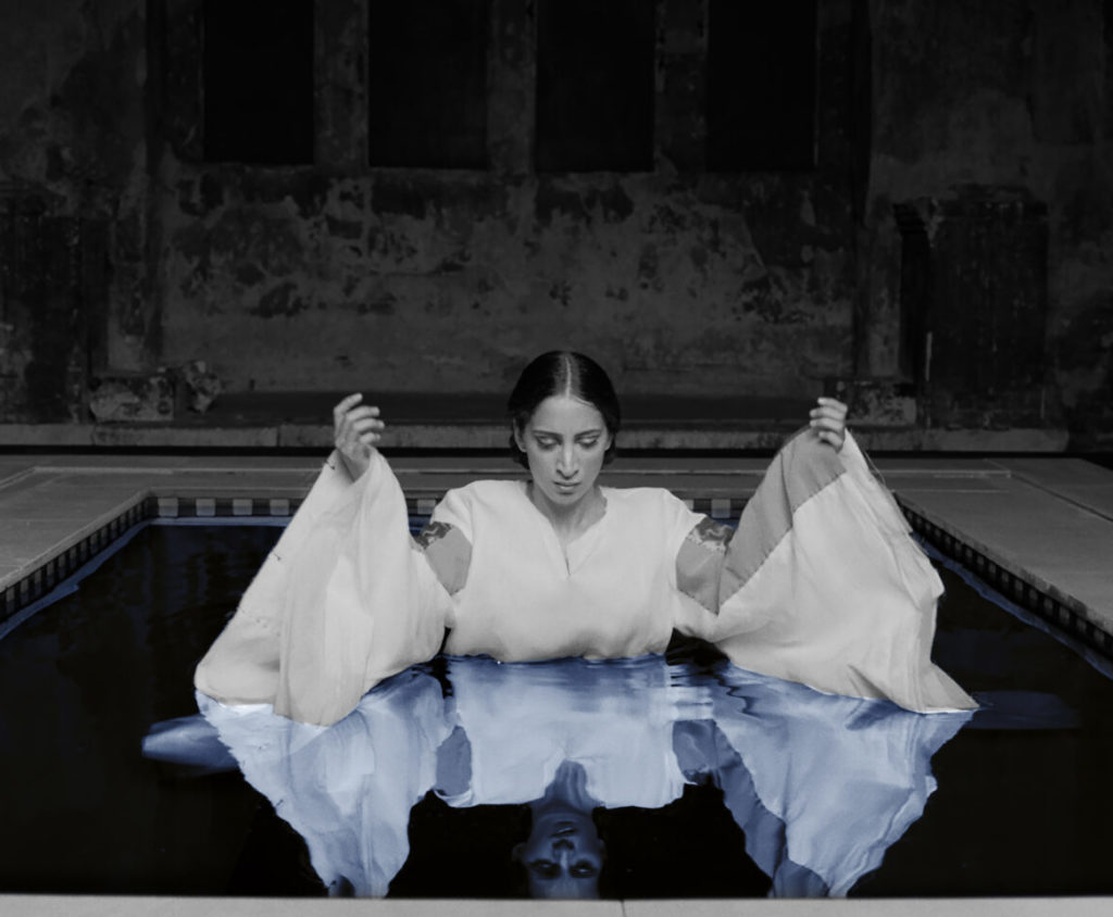 Woman in white, sitting in water.