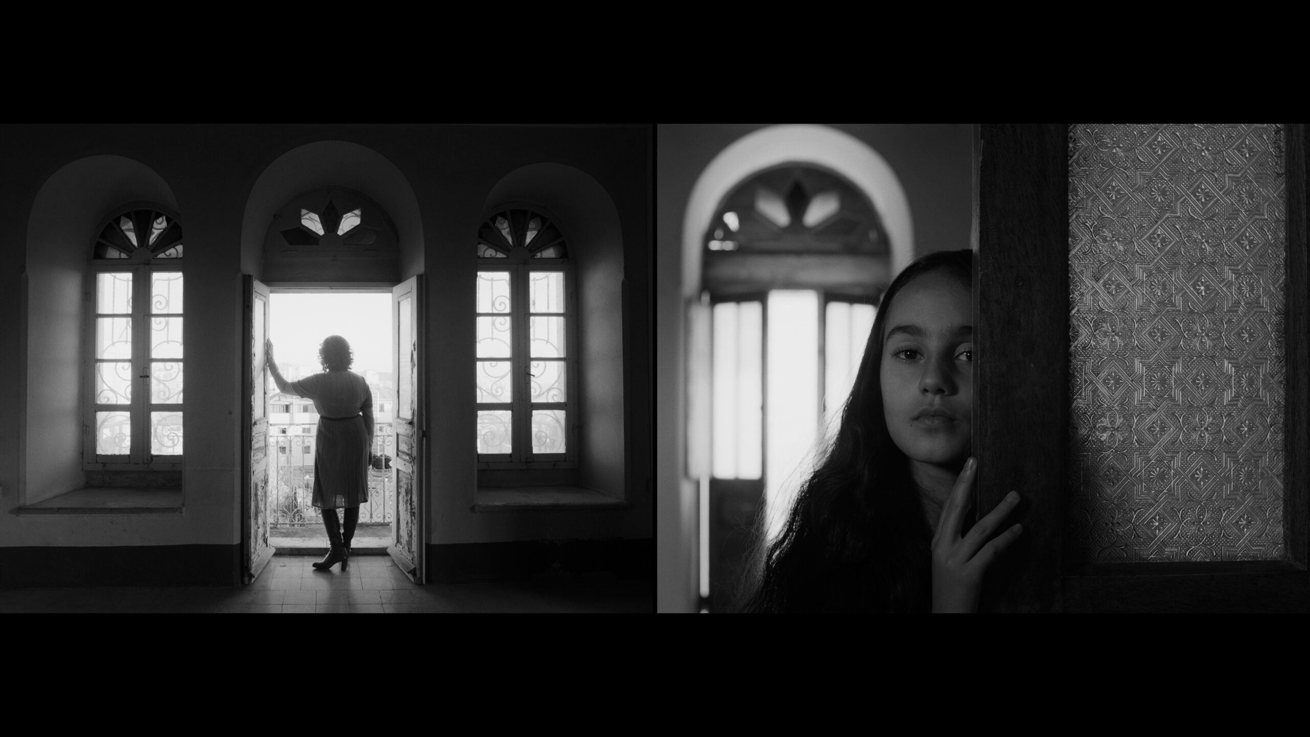 A woman standing in a doorway, and a girl is looking into the camera.