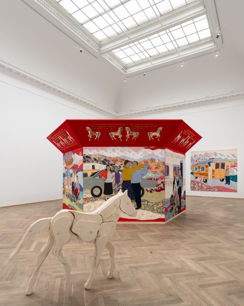 Installationsview af en hest i træ, en skulptur i tekstil og et væghængt tekstilværk.